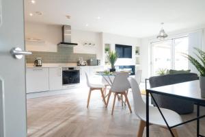 a kitchen and dining room with a table and chairs at Century Central, Cardiff Bay, Modern Chic 2BR, Free Parking in Cardiff