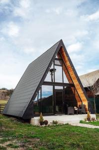 ein Haus mit einem dreieckigen Dach im Gras in der Unterkunft Casuta mea in Stulpicani