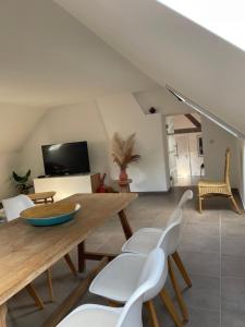 ein Wohnzimmer mit einem Holztisch und weißen Stühlen in der Unterkunft La Canopée des Arbres, Juliette in Ellezelles