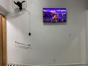 a flat screen tv on a white wall with a fan at Pousada Coração de Jesus in Aparecida