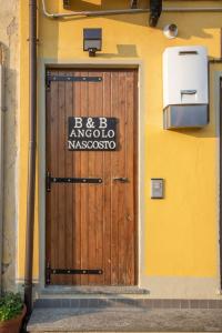 uma porta de madeira com uma placa na lateral de um edifício em B&B Angolo Nascosto em San Fiorano