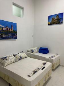 two beds in a room with paintings on the wall at Pousada Coração de Jesus in Aparecida