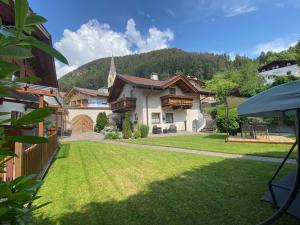 ein Haus mit einem grünen Hof mit einer Kirche in der Unterkunft Sonnenresidenz Malfertheinerhof in Kastelruth