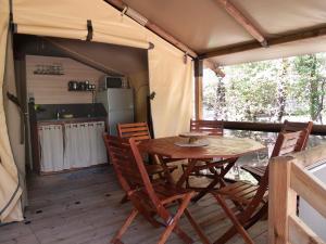 Camping L'Ondine de Provence في La Motte-Chalançon: طاولة وكراسي خشبية في خيمة