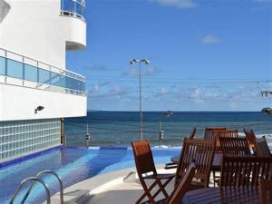 a swimming pool with chairs and a view of the ocean at Vista Top em Ondina in Salvador