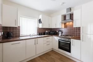 a white kitchen with white cabinets and appliances at Oxheys House - 5 Bedrooms Contractors Parking in Preston