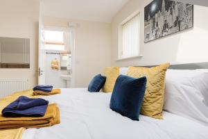 a white bed with blue and yellow pillows on it at Oxheys House - 5 Bedrooms Contractors Parking in Preston