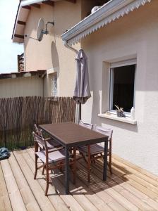 une table en bois avec des chaises et un parasol sur une terrasse dans l'établissement Charmant appartement, à Andernos-les-Bains