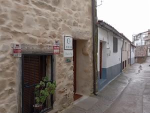 een stenen gebouw met een deur en een bord erop bij Restaurante & Hotel Rural El Mirador de Trevejo in Villamiel