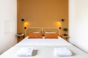 - une chambre avec un grand lit blanc et deux oreillers orange dans l'établissement LIK APPARTS Thabor, à Rennes