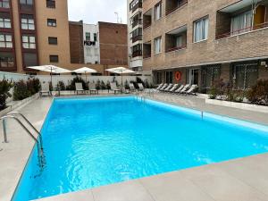 a large blue swimming pool in front of a building at JUAN BRAVO Apartamento a estrenar con PISCINA in Madrid
