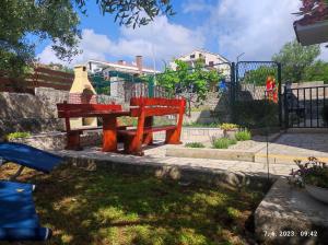 un banc rouge dans un parc à côté d'une clôture dans l'établissement Apartman Luma, à Krk