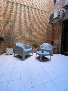 un patio con 2 sillas, una mesa y una pared de ladrillo en Excelente y amplio dpto 3 dormitorios c cochera privada en Mendoza