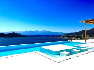 a swimming pool with a view of the water at New Serenity Art Villa Elounda in Elounda