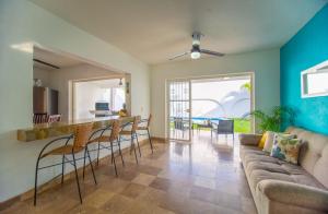 Una sala de estar con un sofá y un bar con sillas. en Casa Melanie, Alberca y Asador Privados, en Puerto Vallarta