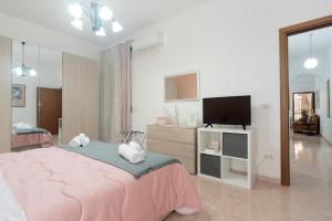 a bedroom with a pink bed and a flat screen tv at Nina Home - Selfcheck-in in Canicattini Bagni
