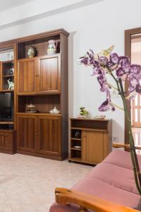 a living room with wooden cabinets and a purple flower at Nina Home - Selfcheck-in in Canicattini Bagni