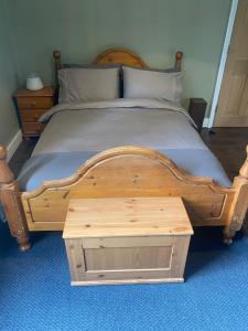 uma cama de madeira com uma tábua de pés de madeira e uma mesa em Tranquil Garden View Double Room em Londres