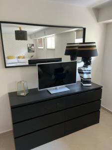 a black dresser with a monitor and a lamp on it at Apartament Kwaskowa Góra in Kazimierz Dolny