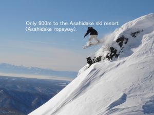 a man riding a snowboard down a snow covered mountain at Asahidake Yumoto Yukomanso in Higashikawa