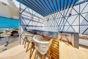 a balcony with three chairs and a bar with a view at One Paralia 405 in Playa del Carmen