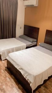duas camas num quarto de hotel com lençóis brancos em مدينتي em Madinaty