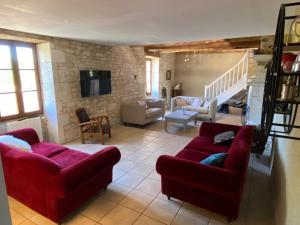 een woonkamer met twee rode banken en een trap bij Gite Domaine Des Pierres Blanches in Belmontet