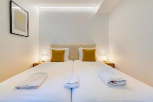 ein Schlafzimmer mit einem großen weißen Bett mit gelben Kissen in der Unterkunft Your Perfect Pantheon Stay in Lissabon