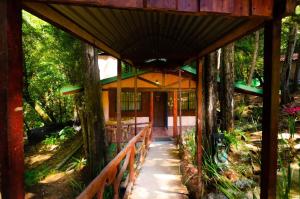 ein Haus im Wald mit einer Veranda und Bäumen in der Unterkunft Cabañas Lunas del Poás 