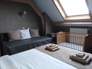 a bedroom with a bed and a crib with towels at 't Hooghe Licht Bed & Breakfast in Zonnebeke