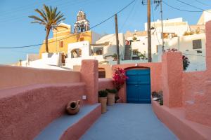 a view of a house with a blue door and buildings at Amphora Villas Oia Santorini in Foinikiá