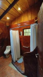 a bathroom with a toilet and a shower curtain at Cabañas Lunas del Poás 