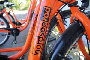 un gruppo di biciclette arancioni parcheggiate l'una accanto all'altra di Nordseehotel Wilhelmshaven a Wilhelmshaven