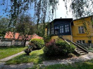 a yellow house with a black roof and a yard at ApartmentVillaSolomon7 in Visegrád