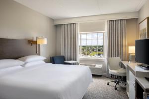 Sheraton Jacksonville Hotel في جاكسونفيل: غرفه فندقيه بسرير ومكتب ونافذه