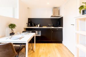 a kitchen with a white table and black cabinets at LIK APPARTS - La Courrouze Rennes in Rennes