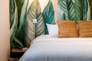 a bed with two pillows and a wall with leaves at LIK APPARTS - La Courrouze Rennes in Rennes