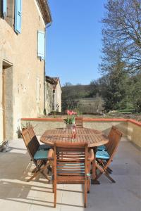 Une table et des chaises en bois sont disponibles sur la terrasse. dans l'établissement Gîte - La Couderquié, à Lautrec