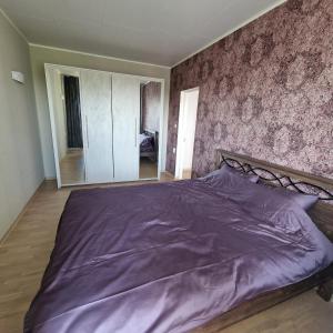 een slaapkamer met een groot bed met paarse lakens bij Hubane 3-toaline korter Roiul 