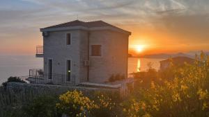 a building on a hill with the sunset in the background at Family Vacation Villa Rezevici in Budva