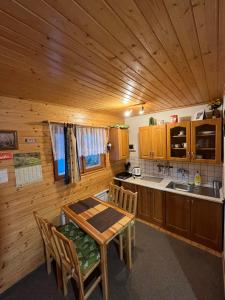 cocina con techo de madera, mesa y sillas en Chata u Porubäna, en Jakubovany