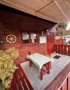 Cabaña de madera con mesa y sillas en el porche en Chata u Porubäna, en Jakubovany