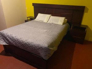 uma cama com uma cabeceira em madeira e 2 almofadas em pusary hostel em Arequipa