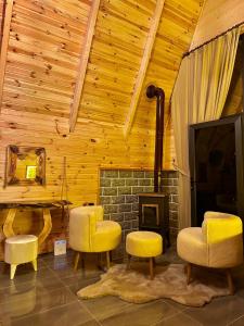 a living room with yellow chairs and a fireplace at SHATOBUNGALOV in Çamlıhemşin