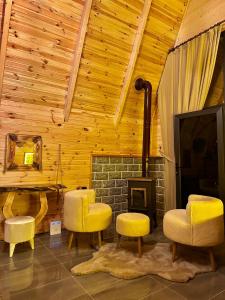 a living room with yellow chairs and a fireplace at SHATOBUNGALOV in Çamlıhemşin +17 photos