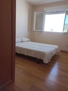 una camera con un letto in una stanza con una finestra di Apartamento delante de la playa. a Ribeira