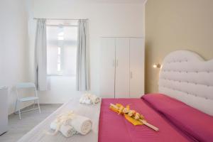 una camera da letto con un grande letto bianco con lenzuola rosa di CalaBisso a Calasetta