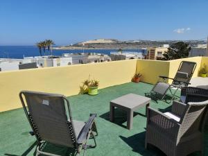 un patio avec des chaises et une table sur le toit dans l'établissement Sunshine Holiday Apartment 5 with Spectacular Seaviews, à San Pawl il-Baħar