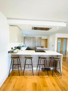 a kitchen with a white counter and three bar stools at Woodland View Stunning Spacious 5 Bedroom Holiday Home in Saint Lawrence