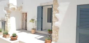 um edifício branco com portas azuis e vasos de plantas em Gárgara Bed and Breakfast em Vico del Gargano